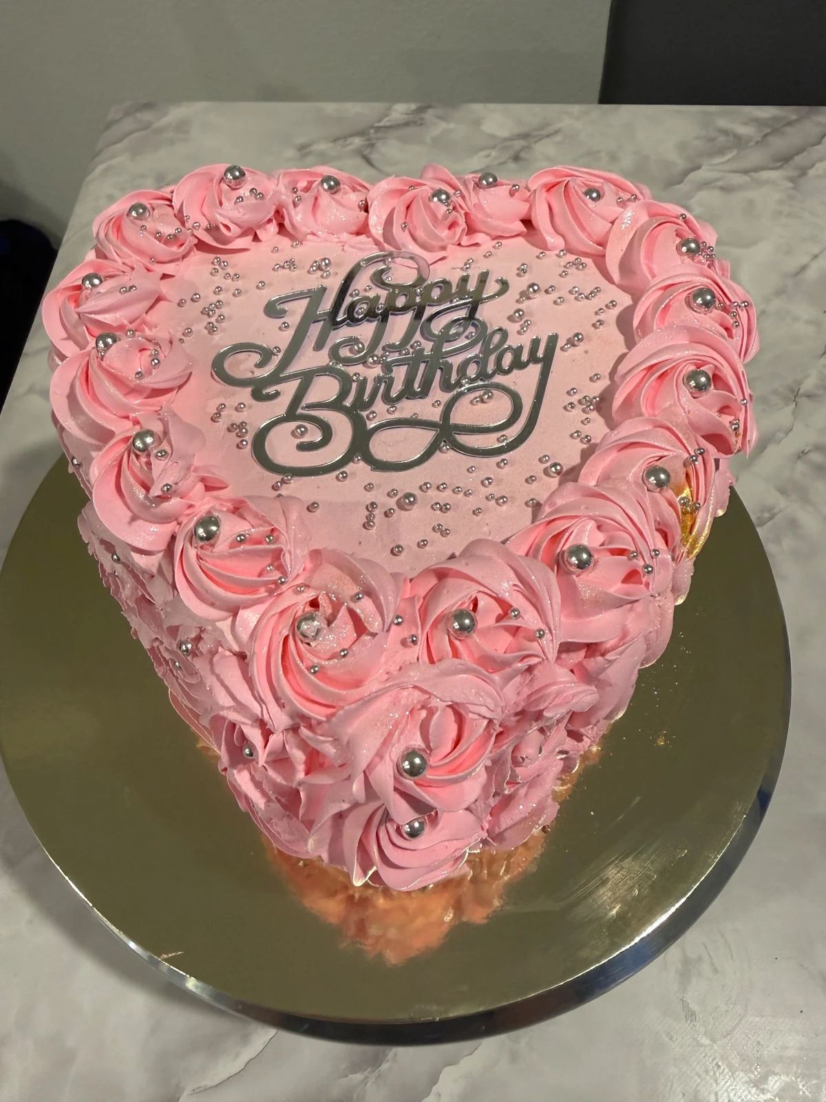 Pink heart-shaped cake with buttercream rosettes and silver pearls