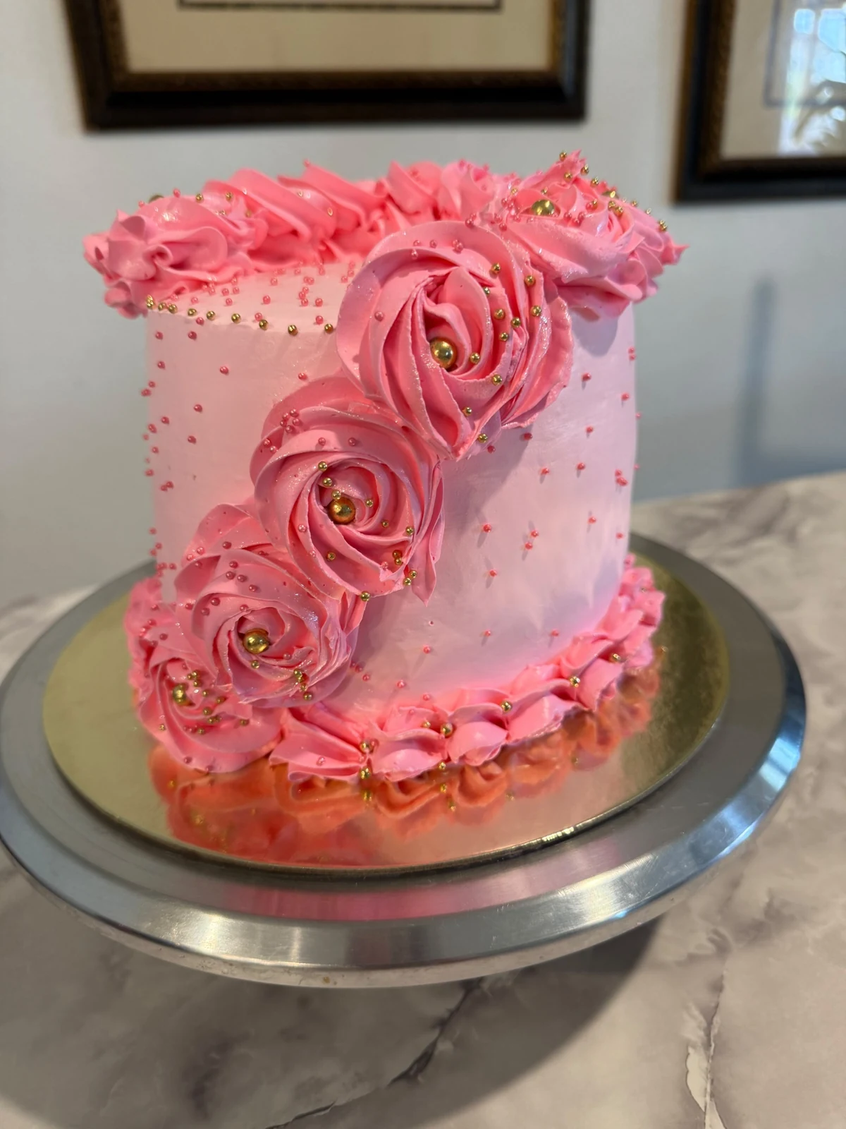 Pink cake decorated with cascading buttercream rosettes and gold pearls